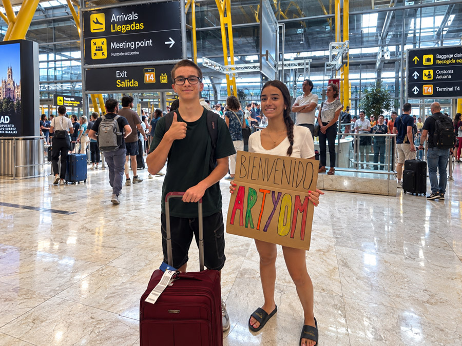 Una familia recibe a un ni&ntilde;o de intercambio en la estaci&oacute;n con un cartel de bienvenida